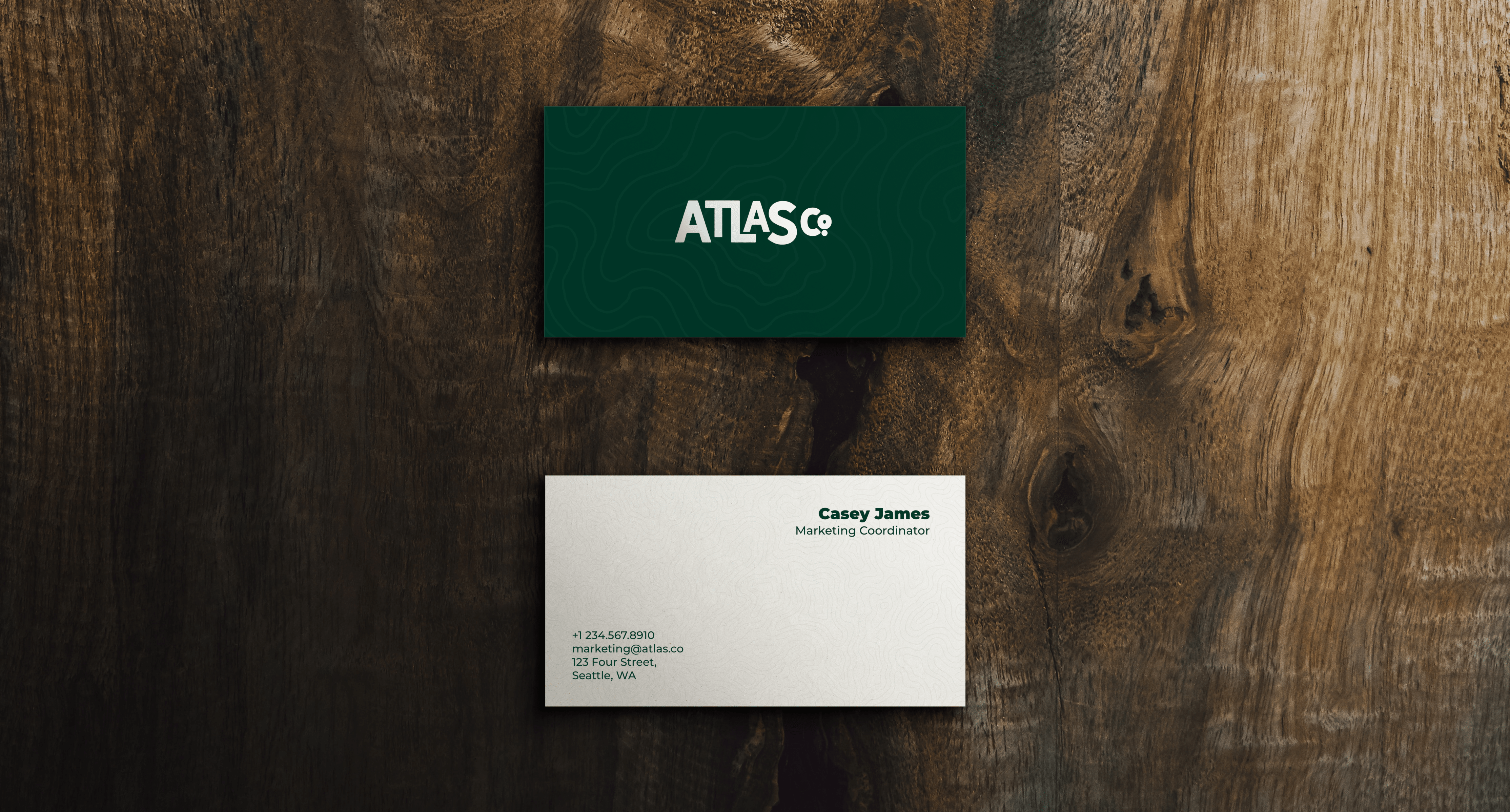 Logo for Atlas Co on business cards with a topographic map background.