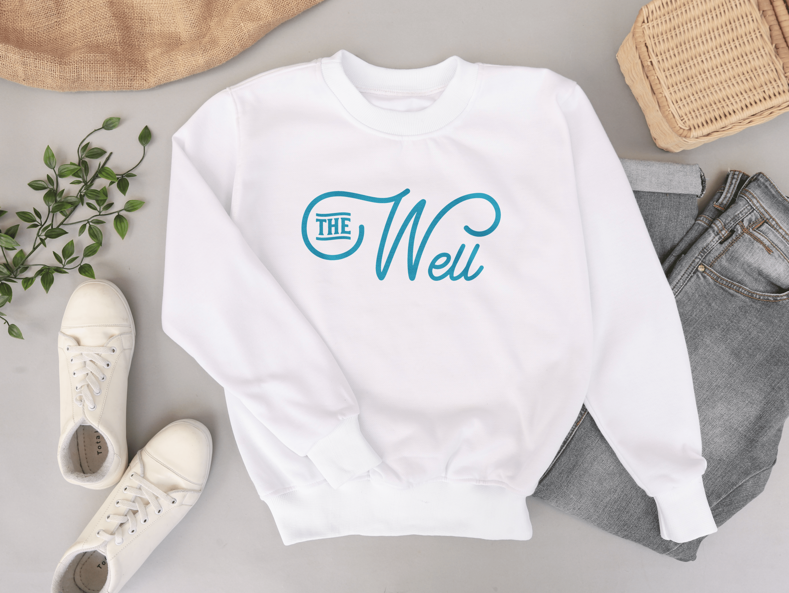 Logo for The Well in blue on a white sweatshirt.